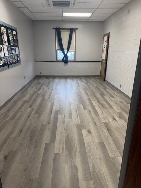 Commercial office room finished in grey wood-look plank flooring, laid wall to wall beneath a curtained window
