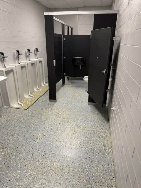 School restroom with a gray decorative flake floor beneath stalls